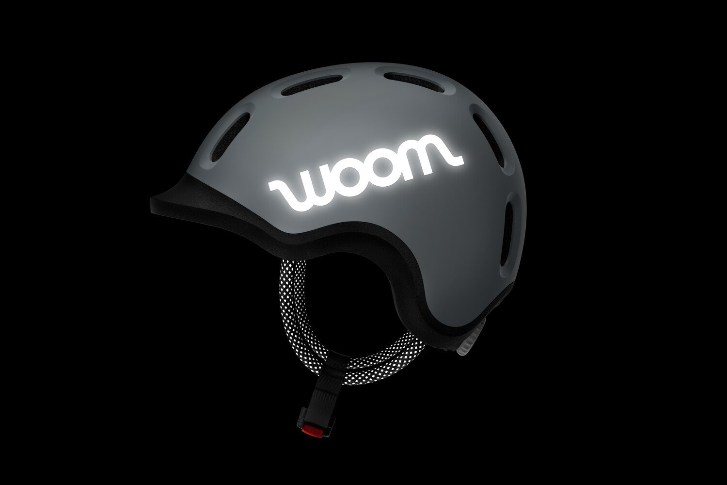 Abgedunkelte Seitenansicht eines grauen READY Kinderhelms mit reflektierendem woom Logo und reflektierender Kordel