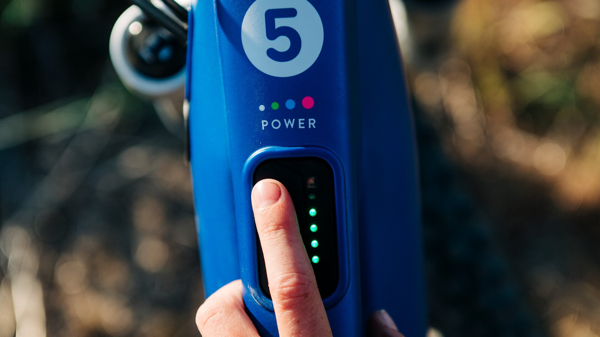 Zeigefinger wählt die Unterstützungsstufe am blauen E-Bike woom UP aus.